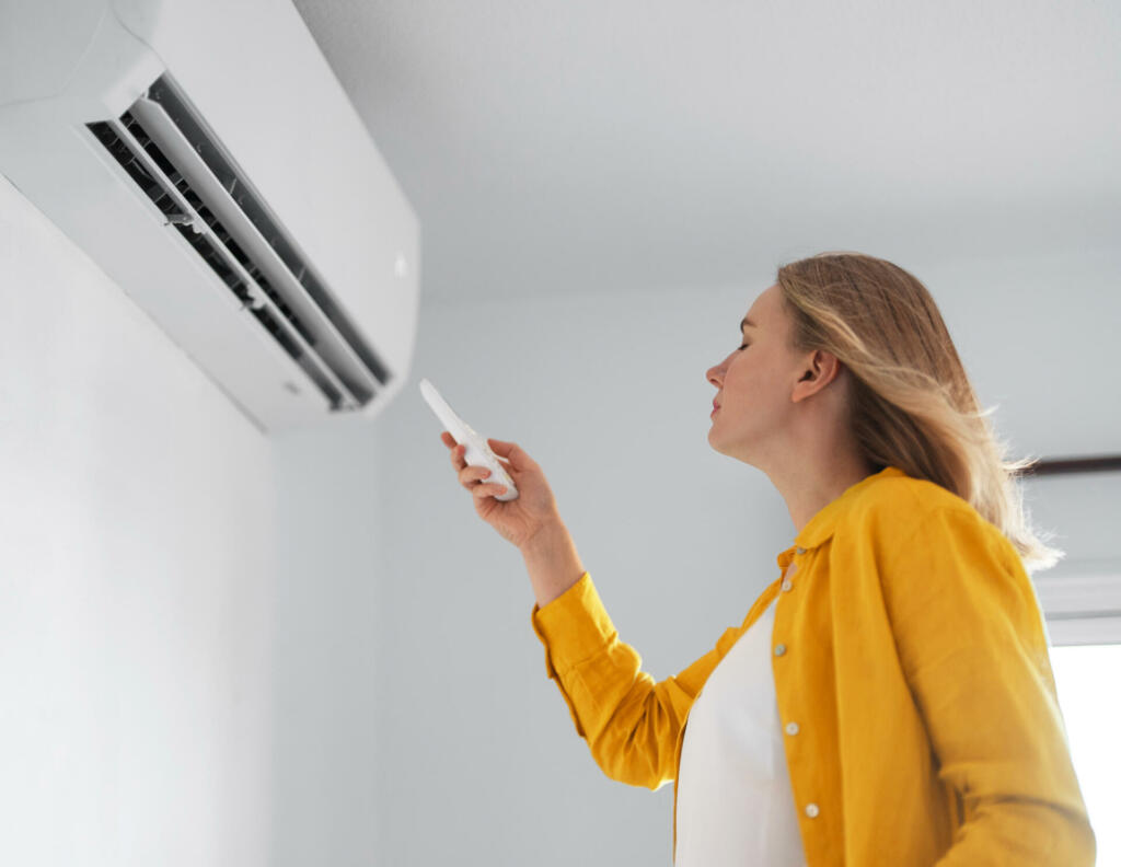 Women dying from the heat standing in front of the air conditioner.