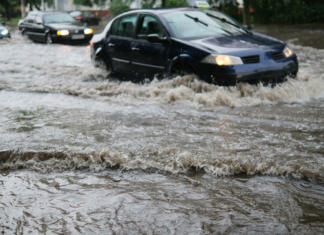 Poletna neurja pri nas vse močnejša: kaj storiti, če poplavi notranjost avtomobila? Avtomobilski promet na poplavljeni mestni ulici med močnim dežjem.