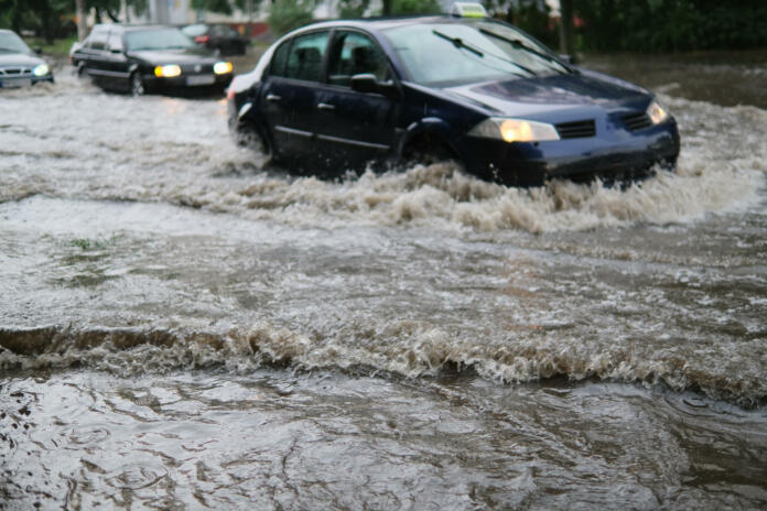 Avtomobilski promet na poplavljeni mestni ulici med močnim dežjem.