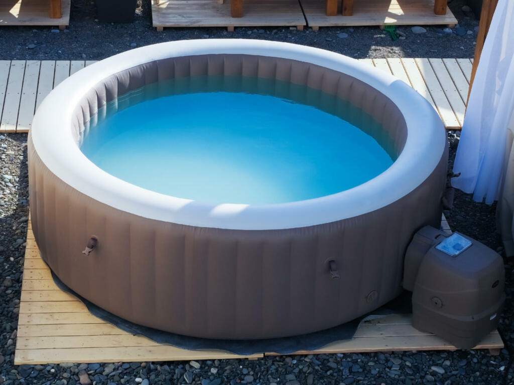 Inflatable brown and white swimming pool with turquoise water outdoors in the summer sun at beach recreation area