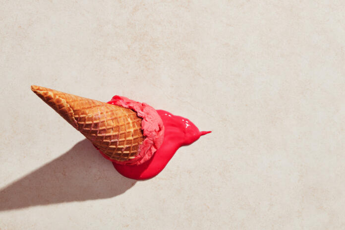 Strawberry ice cream with waffle cone dropped on the floor and melting on the ground under hot summer light. Flat lay view