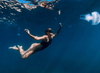 Pozor! Teh živali na Jadranu se morate paziti… Woman underwater with jellyfish in blue ocean. Lady glides underwater in transparent sea