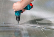 Kako zaščititi polikarbonatno kritino pred točo in podaljšati njeno življenjsko dobo Worker screwing screw into polycarbonate. Building greenhouse