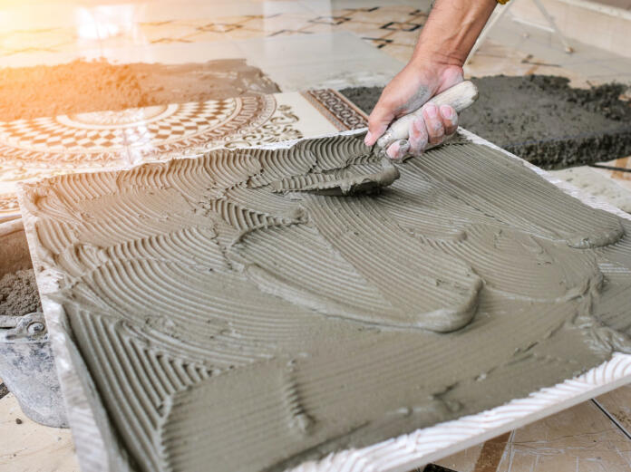 Worker use trowel putting cement on the floor tile