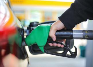 Nove cene bencina in dizla – kako se bodo primerjale s tujino? Close up hand holding green gasoline fuel nozzle and being fill gas tank of black car in gas station Concept of Global Fossil Fuel Consumption Replace by alternative energy in near the near future