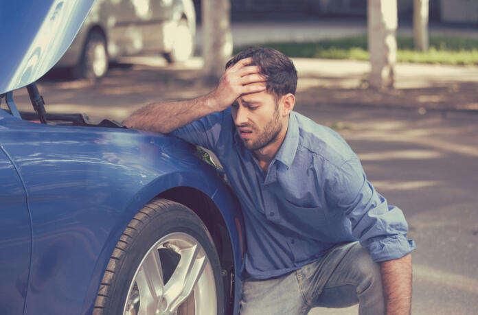Man with broken down car flat tire in the middle of the street