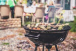 Simple round charcoal barbecue grill closeup. Grilling veggies outdoors for vegan party.  Ash flying around.