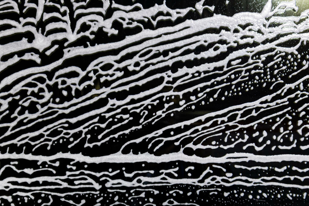 background for washing windows, a lot of active foam on the glass, cleaning and washing black windows. Background with foam