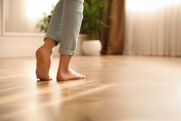 Barefoot woman at home, closeup. Floor heating system