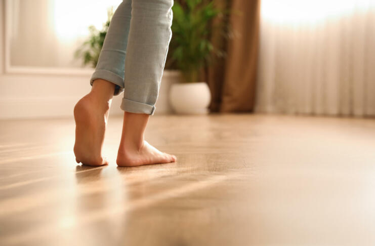 Barefoot woman at home, closeup. Floor heating system