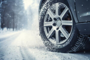 Car on winter tires drives through a snow-covered road. Seasonal change of tires from summer to winter