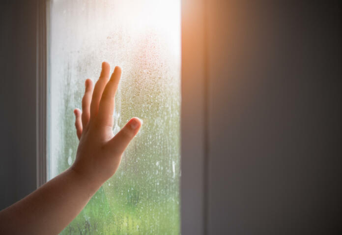 Fingers on the glass with water droplets. Hand child with fogged on the window. Drops of rain on glass background. Selective focus. alone concept