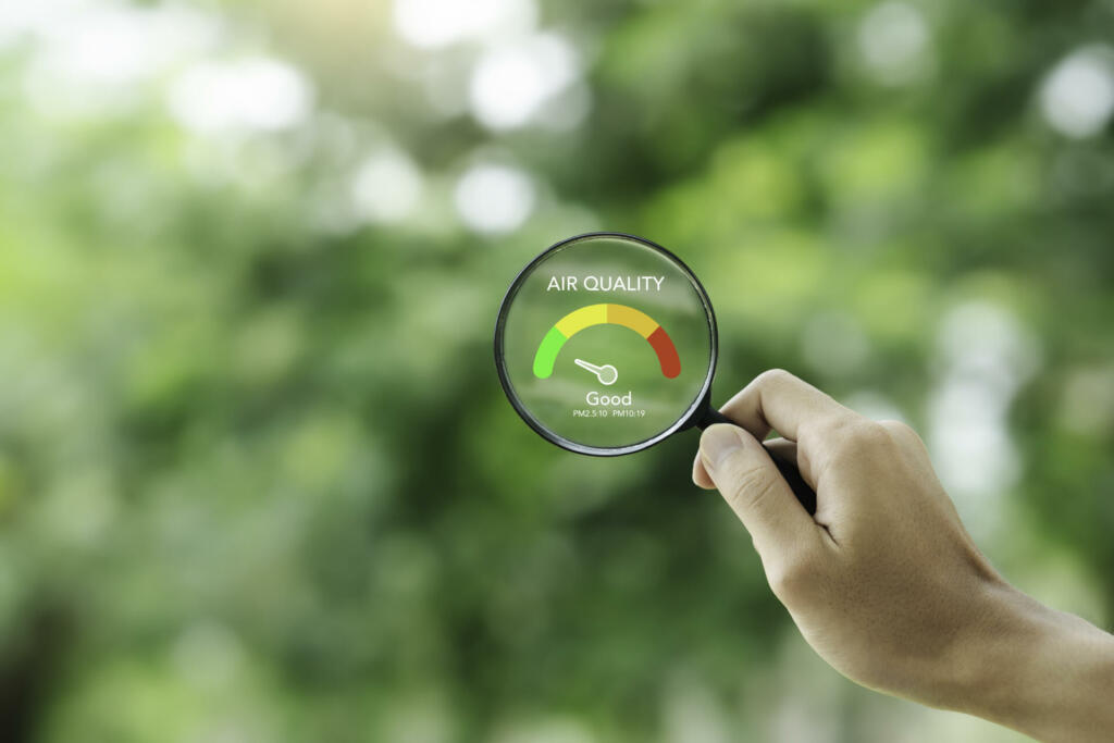 hand holding a magnifying glass to check the good air quality and clean outdoor air quality safe from pollution dust PM 2.5