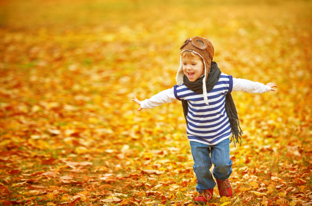 happy child playing pilot aviator and dreams outdoors in autumn