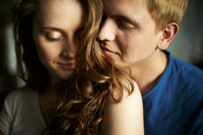 Young man enjoying smell of hair of his sweetheart