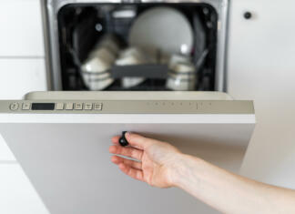 Vaš pomivalni stroj je neučinkovit? Ponujamo 5 načinov za izboljšano delovanje Cropped view of person's hand closing dishwasher with dirty utensils. Contemporary kitchen appliances. Home comfort. Concept of cleanliness. Kitchen interior design details