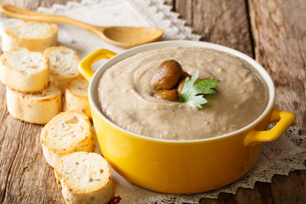 Delicious chestnut soup close-up in a pot and croutons on a table. horizontal