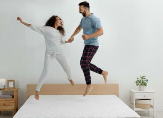 Zakaj je pomembno izbrati kakovostno posteljo? Happy couple jumping on bed with comfortable mattress at home