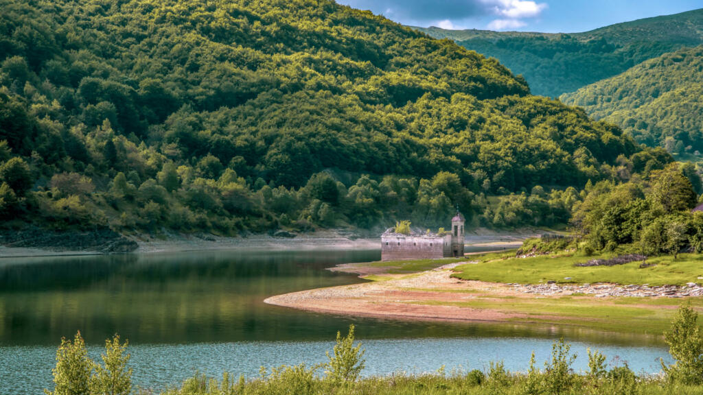 Landscape side view of old church of St Nicholas. Usually partially submerged in Lake. Spring in National Park Mavrovo, North Macedonia.