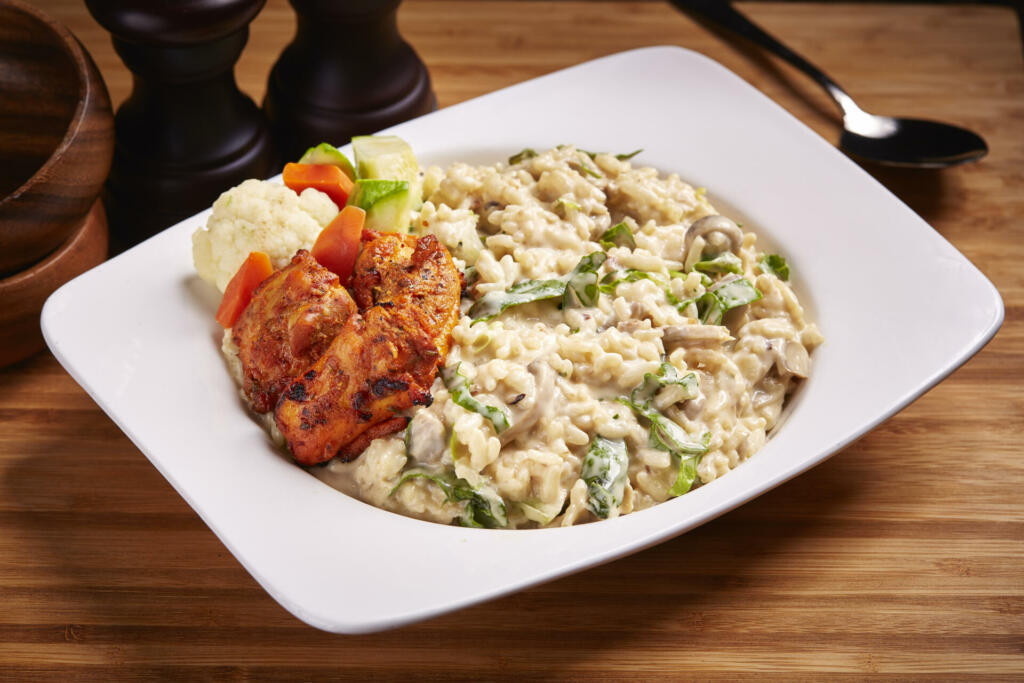 Risotto Mushroom and cubes of chicken served in dish isolated on table side view of middle east food