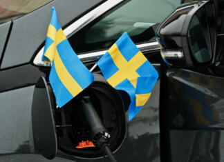 Stockholm počasi prepoveduje vozila s fosilnimi gorivi Sweden flag ecological car concept. Plugging a power supplier, charging modern automobile.