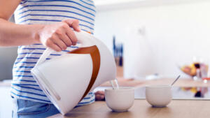 Unrecognizable woman preparing coffee or tea. Pouring water into a cup.