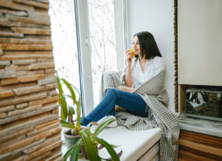Zakaj je prezračevanje pomembno young and pretty brunette sitting by the window in the kitchen with lemon