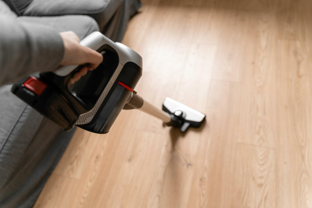 Cleaning wooden floor with wireless vacuum cleaner. Handheld cordless cleaner. Household appliance. Housework modern equipment. High quality photo