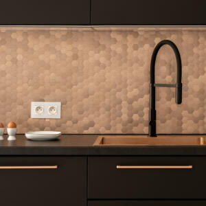 Close-up on elegant kitchen with black countertop, cupboards, drawers and tap and with copper sink, furniture handles and hexagonal wall tiles
