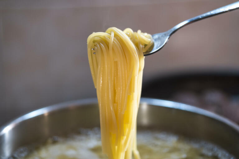 Closeup of spaghetti in pot on stove. Spaghetti in hot boiling water. Take it from the pot with a fork and watch it cook. Spaghetti is ready to cook at home.