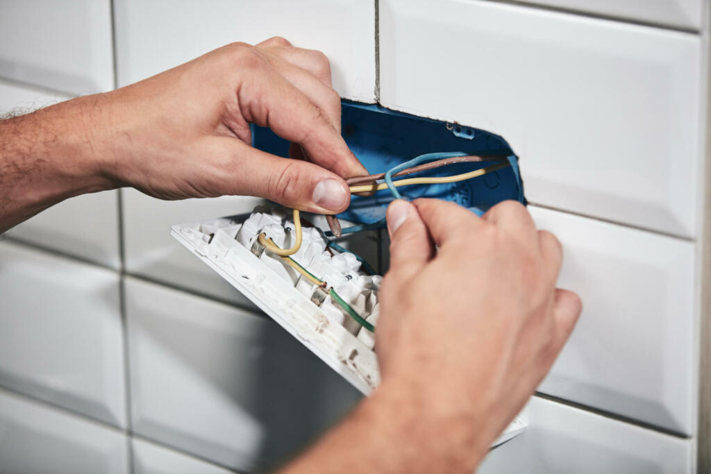 Electrician repairing and fixing wires in the electrical socket.