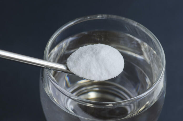 Spoon of baking soda over glass of water