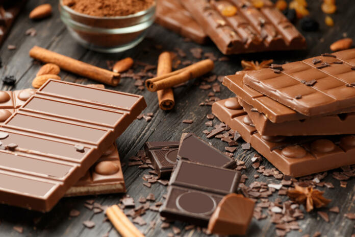 Whole and broken chocolate, chocolate bars, candies, chocolate chips on a dark wooden background