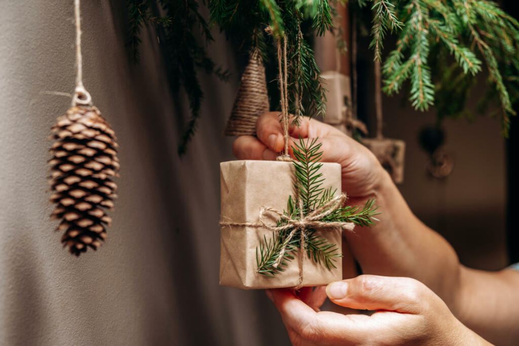 Christmas decor on the wall.Fir branches decorated with gift boxes in craft paper and fir cones.Eco-friendly concept.New Year and Christmas concept.Selective focis,close up.