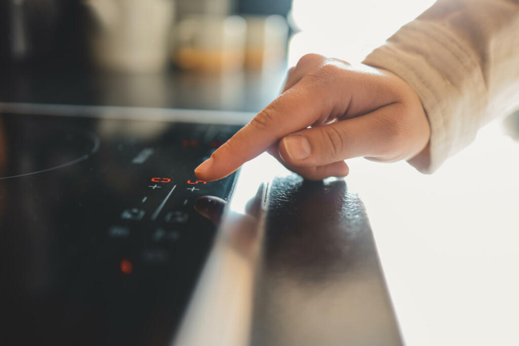 Close-up of turning on electric stove. Action. Turning on electronic plate panel. Panel with touch buttons on electronic plate.