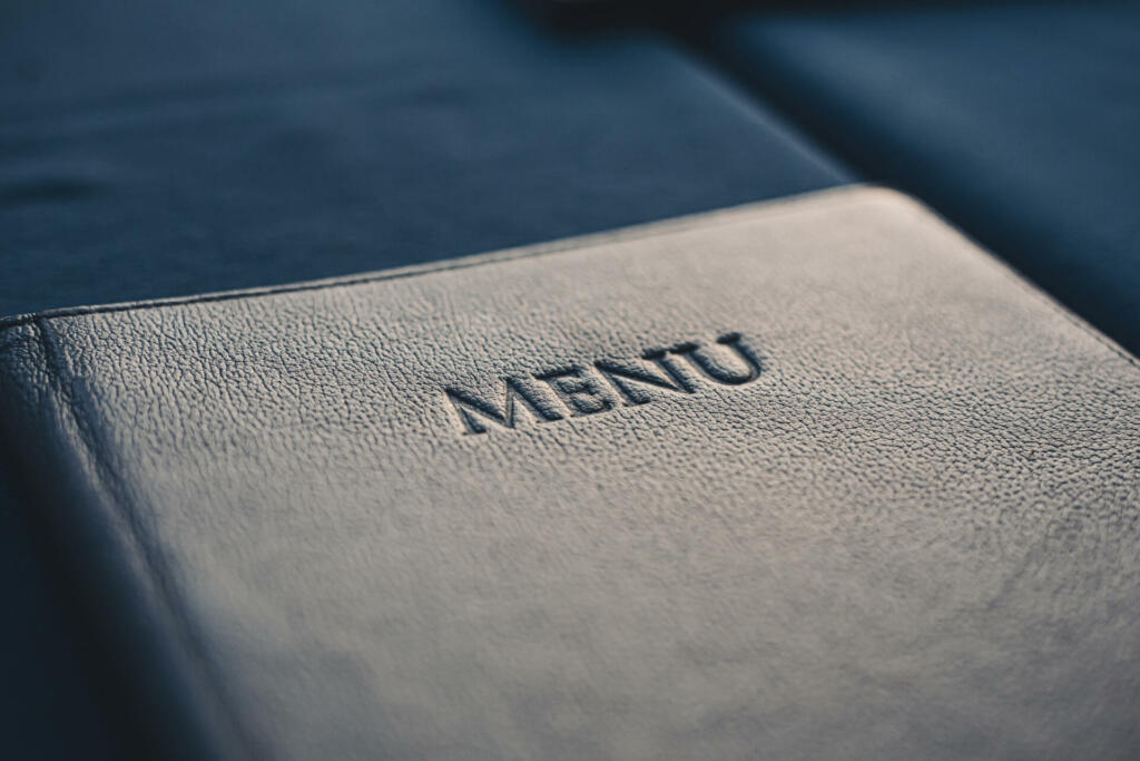 Dark blue menu book on table in restaurant, selective focus closeup