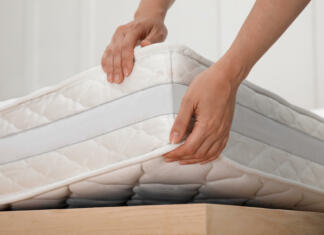 Kaj se zgodi, če izberemo napačno vzmetnico? Woman putting soft white mattress on bed indoors, closeup