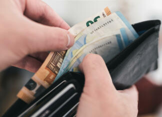 Mesec določil, kakšna bo minimalna plača v letu 2024, sindikati obžalujejo zamujeno priložnost close-up view of hands taking money out of a wallet, spending cash concept