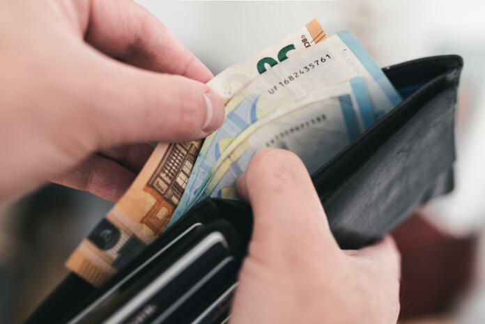 close-up view of hands taking money out of a wallet, spending cash concept