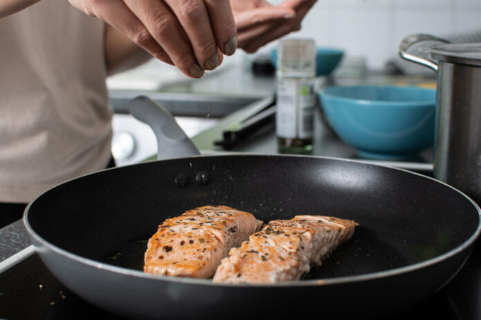 cooking healthy food and adding spices to food in a frying pan