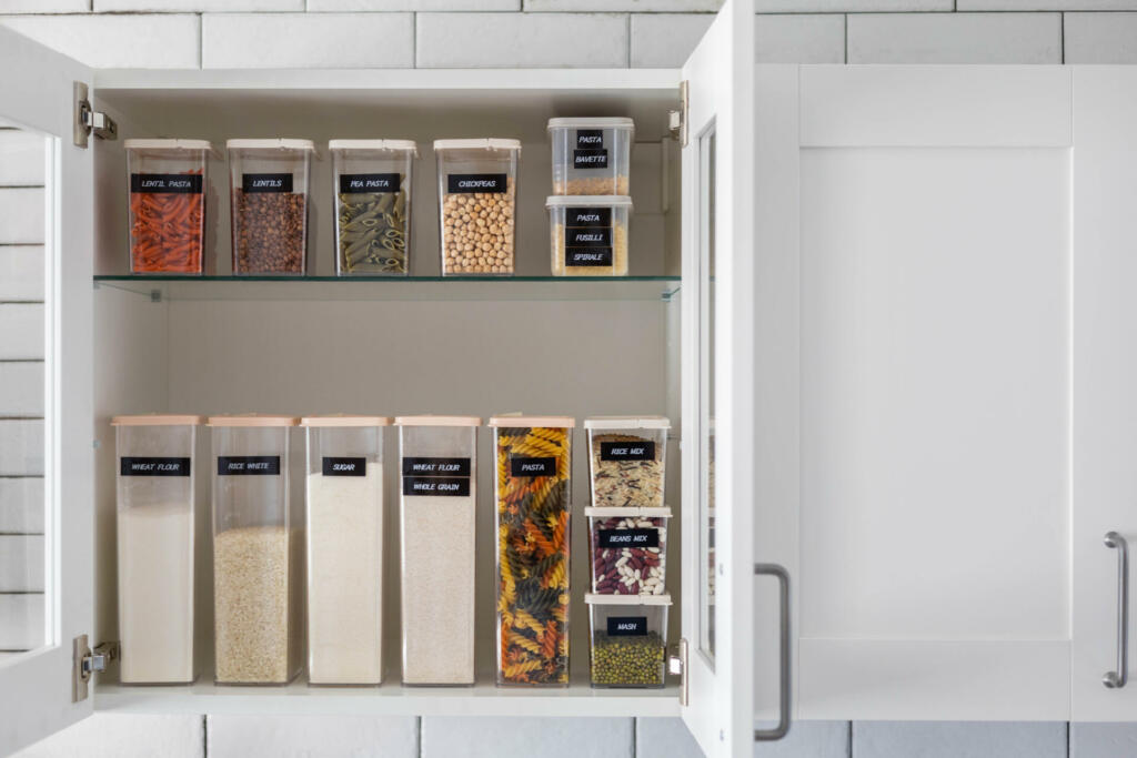 Kitchen storage organization use plastic case. Placing and sorting food products into pp box. Keeping organizing at modern kitchen interior in Nordic style. General cleaning, tidying up at cuisine