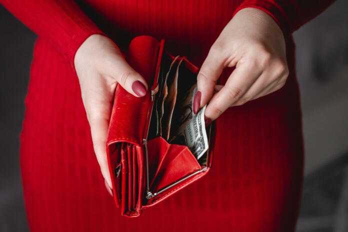 Red wallet in the hands of a woman in a red dress with red manicure