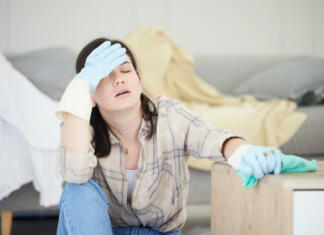5 čistilnih navad, ki se jih morate znebiti Tired, stressed young woman with headache doing spring cleaning chores, sitting in her living room at home. Frustrated, overworked female is exhausted from hygienic domestic housekeeping service