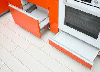 Ste vedeli, da predal pod pečico ni namenjen čiščenju posode, ampak nečemu čisto drugemu? Upscale Maple Red kitchen two drawer for plates or dishes shelf cabinets. Pull out rack cabinets fillers pantry under and near oven. Horizontal drawers shelf with orange front wooden panel, side view.