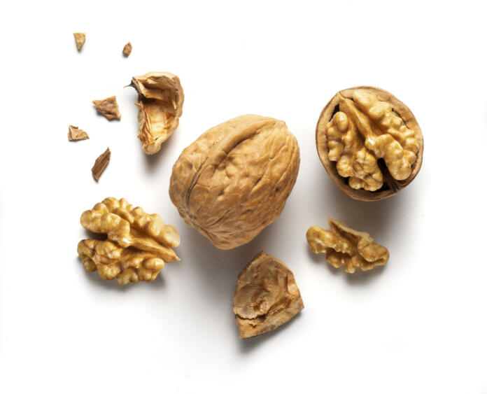 a whole walnut and an open walnut on a white table, top view