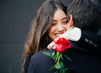 Pazite, kakšno vrtnico boste svoji ljubezni podarili za valentinovo, vsaka barva svoj pomen Beautiful and happy young woman in love hugging her boyfriend holding a red rose