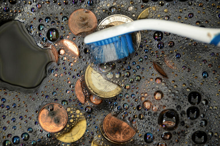 Black Euro coins being washed, suggesting the term "whitewash of black money"