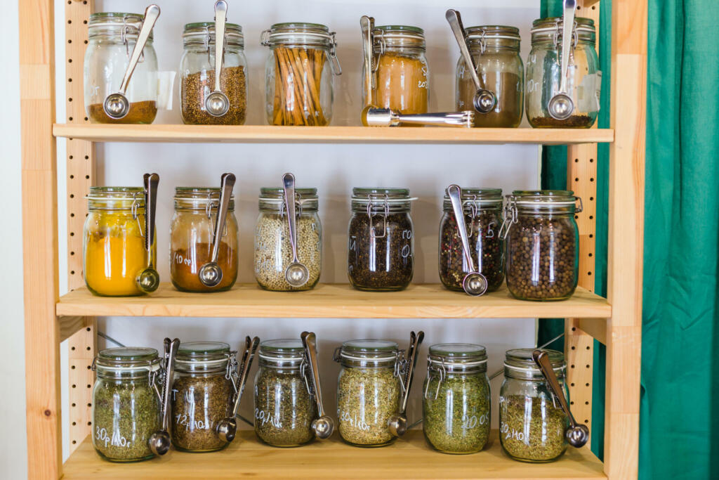 Close up of shelves with a selection of spices and grains in glass jars in zero waste shop