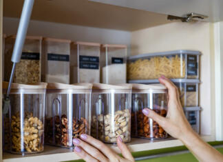 6 nasvetov za organizacijo kuhinjskih omaric Domestic healthy vegetarian dry food storage organization on shelf at kitchen cupboard. Comfortable neatly keeping arrangement in glass containers oat flakes, wheat flour, sugar, pasta, nuts, rice