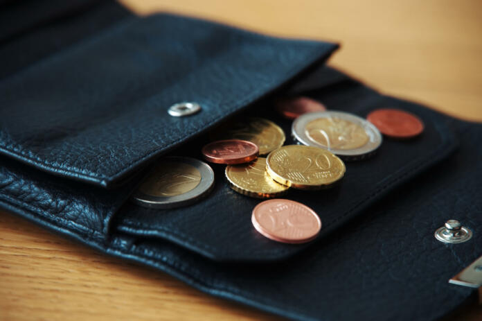 Euro coins in black wallet on wooden table